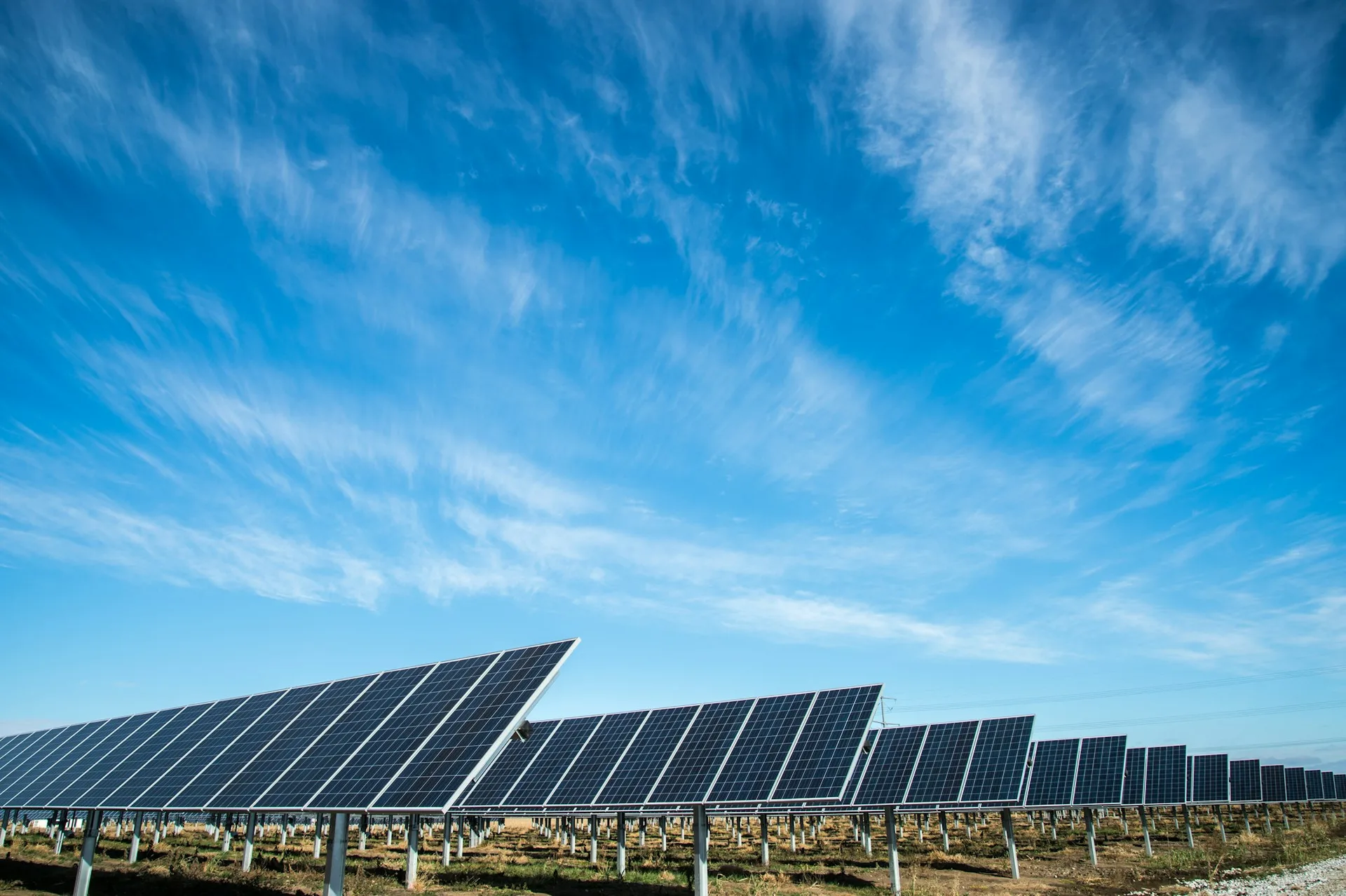 Deretan panel surya yang menangkap energi matahari di tengah lanskap hijau